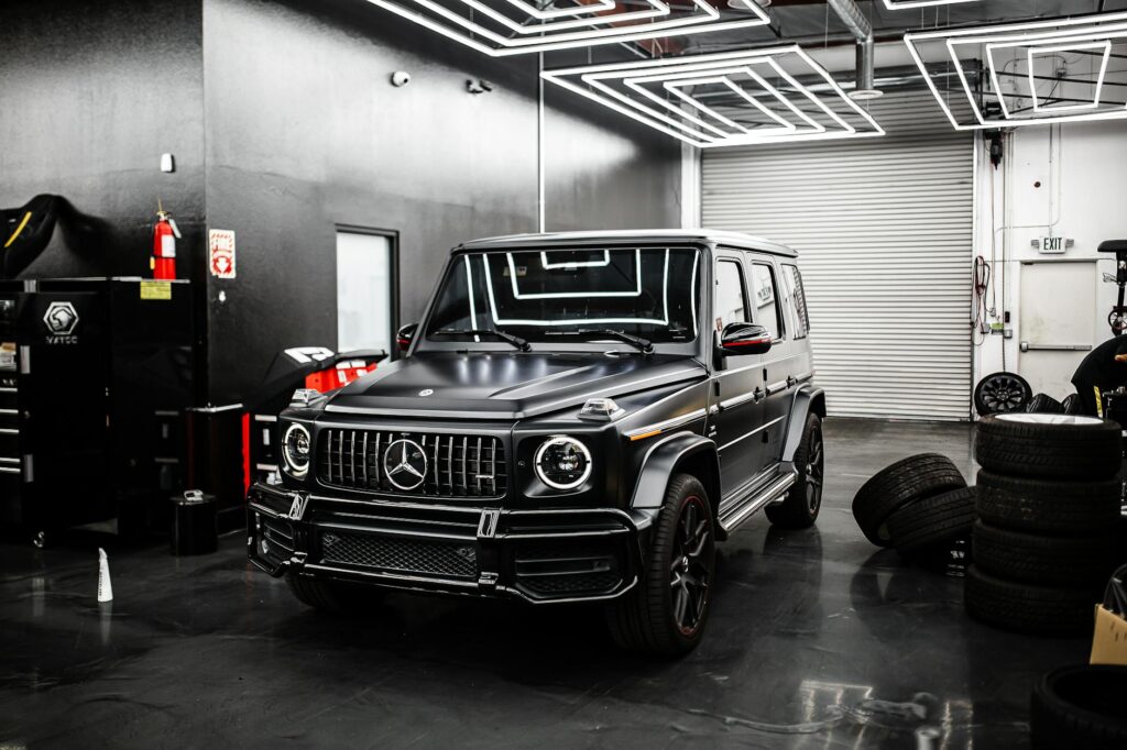 Sleek black SUV parked in a high-end automotive garage. Modern industrial design.