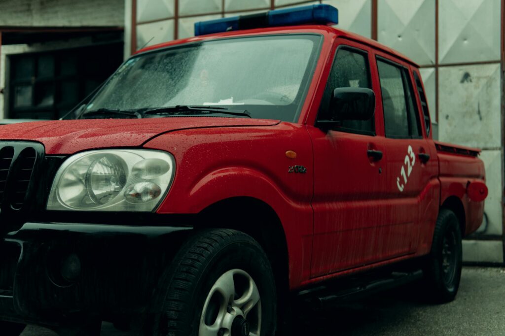 Close-up of a red pickup truck parked in a rainy environment with raindrops visible.