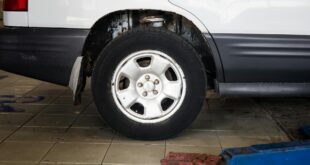 Detailed view of a car wheel in an auto repair shop setting with a hydraulic jack.