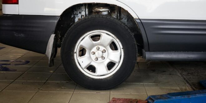 Detailed view of a car wheel in an auto repair shop setting with a hydraulic jack.