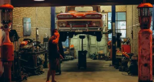 A red vintage truck is lifted in a Bangkok garage. Industrial setting with nostalgic automotive elements.