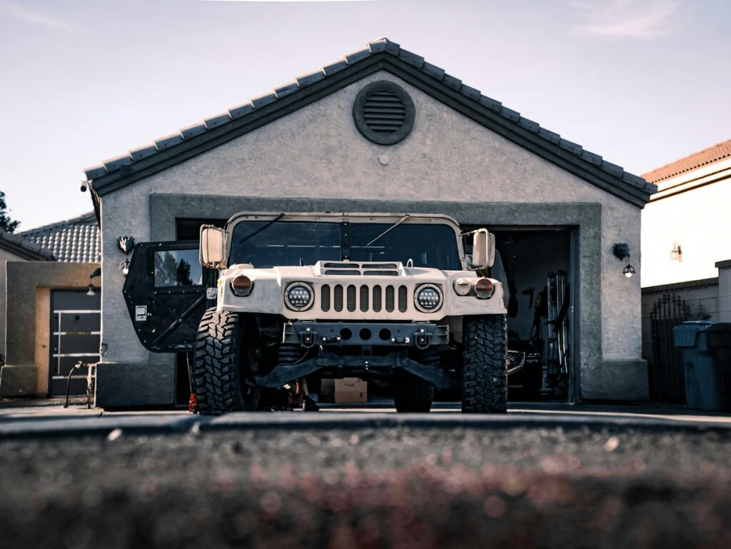 Heavy-duty military vehicle parked in a suburban garage driveway.