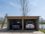 Spacious double garage housing a BMW and Toyota next to a scenic river.