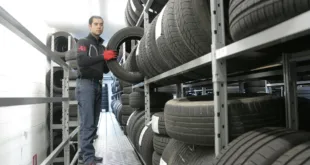 Mechanic places a tire on a rack in an indoor warehouse storage facility.