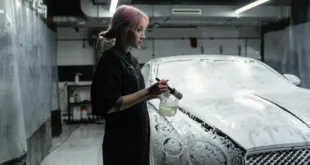Asian woman washing luxury car in indoor car wash with foam.