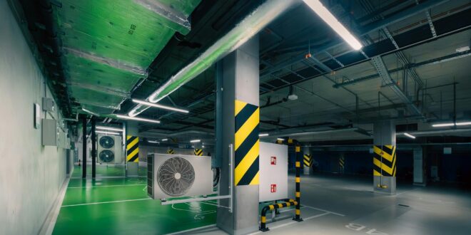 Sleek underground parking area with air conditioning units and green lighting.