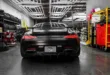 Rear view of a sleek black Mercedes Benz AMG GT in a modern, well-lit garage setting.