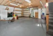 Spacious garage interior with storage shelves, tools, and a wheelbarrow, ideal for home organization.