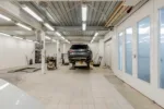Well-lit garage with a car on a hydraulic lift ready for repair.