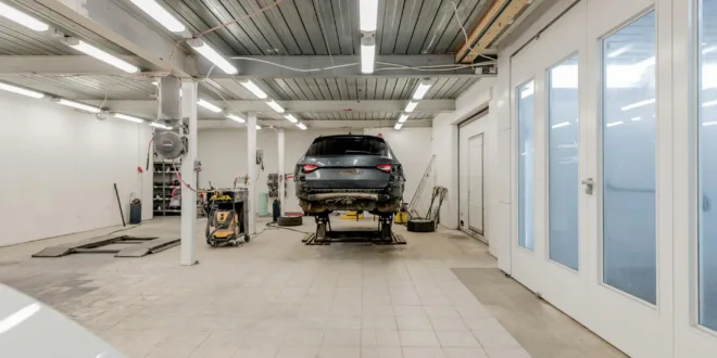 Well-lit garage with a car on a hydraulic lift ready for repair.