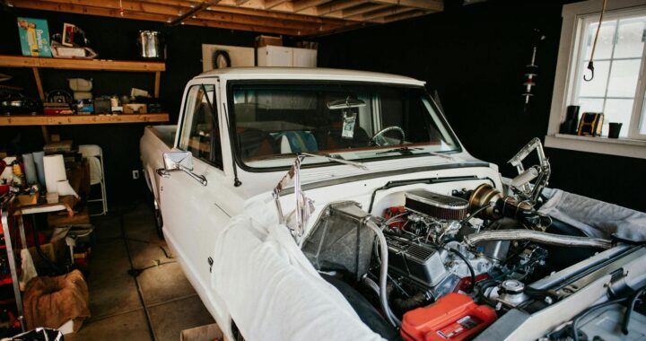 A vintage pickup truck undergoing engine repairs in a well-equipped home garage.