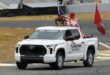 A Toyota Tundra showcasing at a racing event with drivers and flags. Perfect for motorsport enthusiasts.