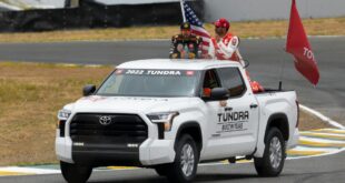 A Toyota Tundra showcasing at a racing event with drivers and flags. Perfect for motorsport enthusiasts.