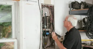 An electrician carefully examines a residential fuse box indoors, ensuring electrical safety and compliance.