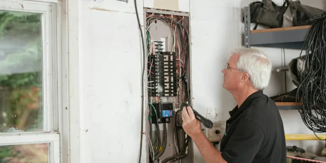 An electrician carefully examines a residential fuse box indoors, ensuring electrical safety and compliance.