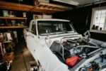 A vintage pickup truck undergoing engine repairs in a well-equipped home garage.