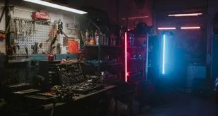 Dimly lit garage featuring neon lights and automotive tools creating a moody ambiance.