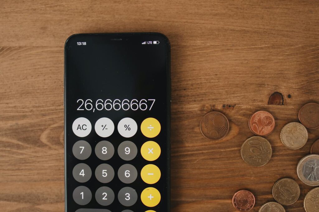 Close-up view of smartphone calculator and coins on wooden surface for financial metaphor.