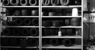 Monochrome image of stacked go-kart tires on sturdy shelves, showcasing various wheel sizes.