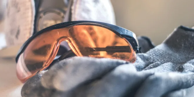 Close-up of safety glasses and gloves with a respirator, highlighting protective equipment.