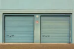 Blue garage doors with a no parking sign painted outdoors.