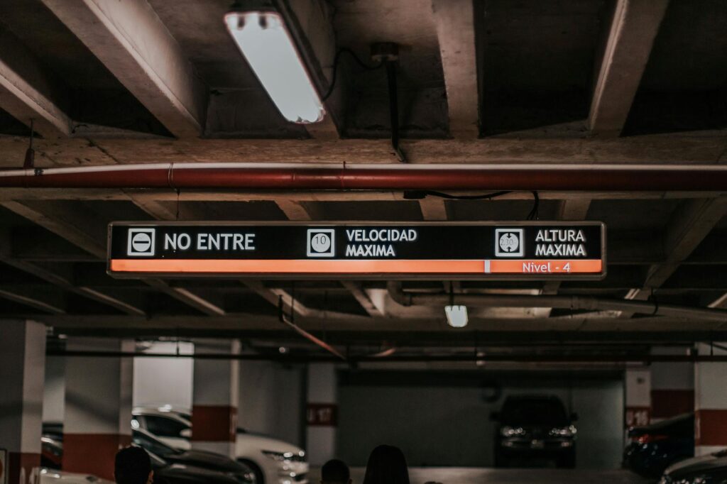 Interior view of a parking garage featuring overhead signage for vehicle height and speed limits.