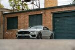 A stylish Ford Mustang parked in front of an old brick industrial building, showcasing automotive design.