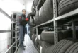 Mechanic places a tire on a rack in an indoor warehouse storage facility.